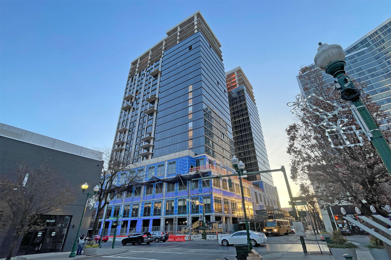 A tall building featuring blue windows stands prominently alongside a bustling street below.
