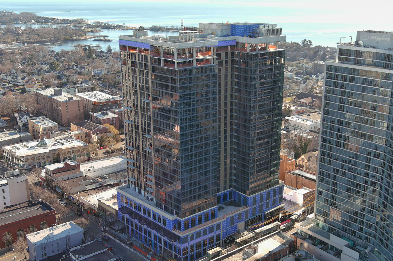 Aerial view showcasing a tall building amidst a bustling cityscape, highlighting urban architecture and surroundings.